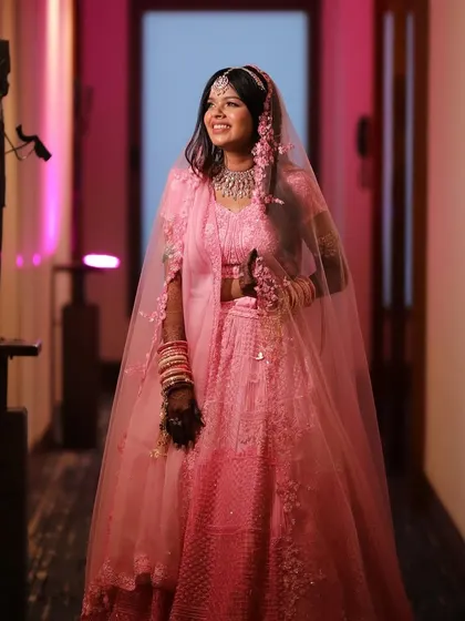 A candid shot of the bride walking down the hallway, her pink lehenga and radiant smile lighting up the space. The makeup is designed to look fresh and beautiful from every angle.