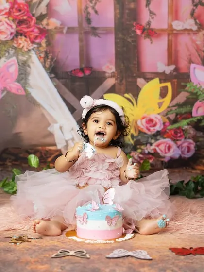 A full shot of the birthday girl enjoying her cake in the beautiful butterfly garden setup.