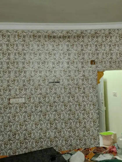 A grey rose-patterned wallpaper installed in a room, with careful cuts around the door frame.