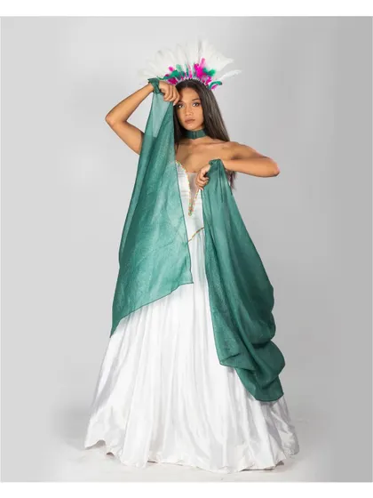 A high-fashion portrait with a carnival-inspired feathered headpiece. The flowing green fabric adds a splash of color and movement against the simple white dress.