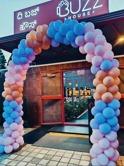 A vibrant balloon arch at the entrance of a restaurant for a private party. The mix of pink, blue, and orange balloons creates a fun and festive atmosphere.