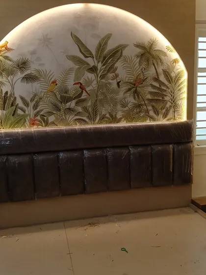 A tropical jungle scene wallpaper used as a unique, arched headboard design. The backlighting enhances the mural, creating a stunning and immersive focal point in the bedroom.