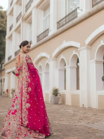 A beautiful shot of the bride looking back over her shoulder, showcasing the intricate details of her lehenga and the elegance of her pose.