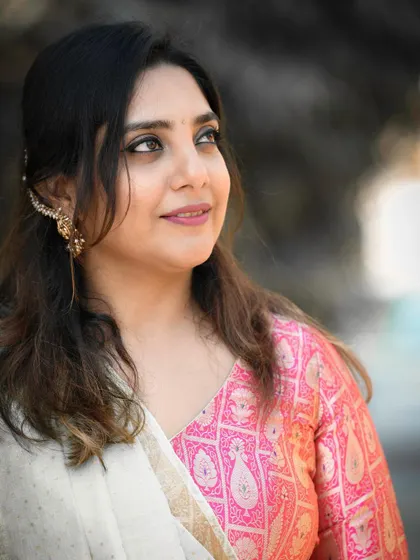 A candid portrait of a woman, likely a wedding guest or family member, during a haldi ceremony. Her natural smile and the soft, diffused light create a warm and beautiful image.