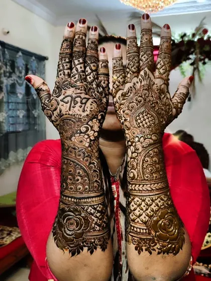 A happy client showing off her bridal henna. This design includes personalized elements like initials hidden within the pattern.