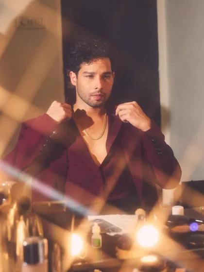 Getting ready. This behind-the-scenes shot of Siddhant captures the mood, with the simple gold chain adding a touch of glam to the deep burgundy shirt.