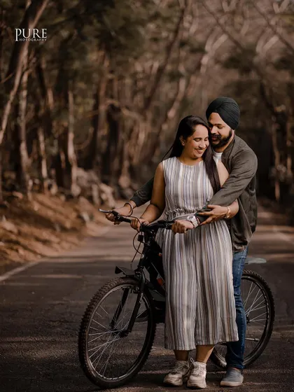 A fun and candid moment with a bicycle on a tree-lined road. This shot from Karan and Simarpreet's pre-wedding session is playful, natural, and full of personality.