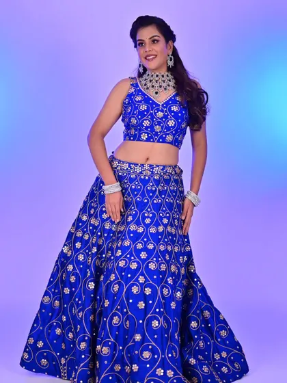 A full-length view of a stunning royal blue lehenga for a reception or sangeet. The makeup is glamorous and bold, designed to match the energy of the outfit and the event.