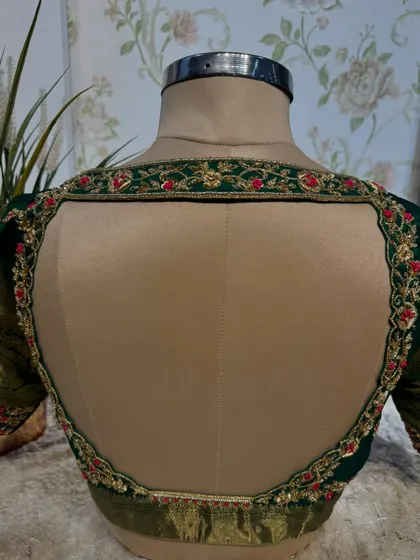 The back of the green blouse, featuring a wide, open design framed by beautiful floral embroidery.