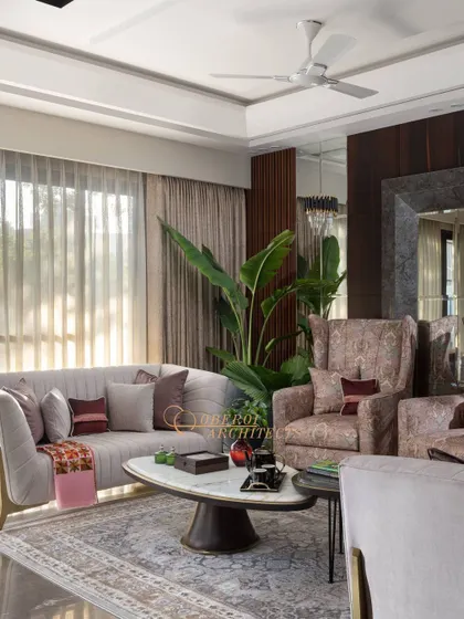 This living room design features cream accent sofas and cozy armchairs, adorned with lush green plants for a refreshing touch.
