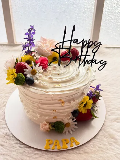 A vibrant cake perfect for a father's birthday. It's topped with a beautiful arrangement of fresh, colorful flowers and berries for a natural, garden-fresh look.