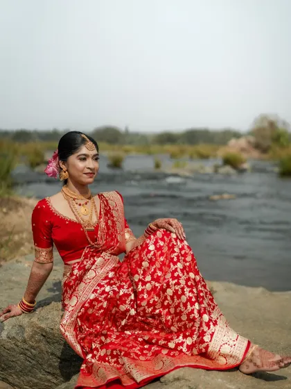 Another stunning shot from the outdoor session, showcasing the full length of her beautiful red brocade saree and elegant makeup.