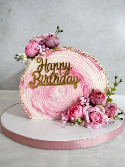Trying out the cake-top-forward trend! This unique design presents the cake on its side, showcasing the beautiful pink swirl texture and floral decorations.