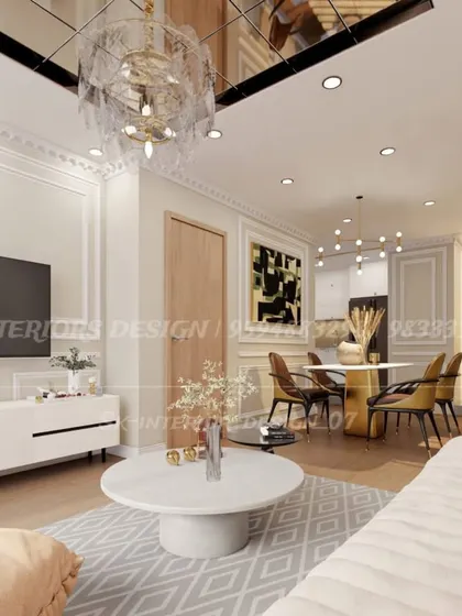 A bright and airy living room with classic wall molding and a reflective ceiling panel. The design combines a modern TV console with elegant furniture for a transitional look.
