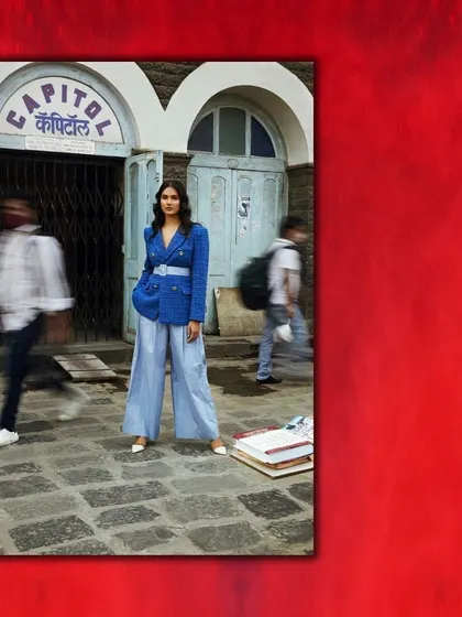 A street-style editorial where a structured blue blazer and wide-leg trousers stand out against a motion-blurred city backdrop. The styling creates a moment of stillness and power in a bustling environment.