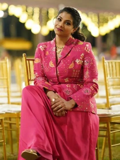 A full-length shot of the client looking poised and confident in her custom pink jacket ensemble.