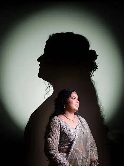 An artistic silhouette portrait of a bride against a spotlight, creating a dramatic and elegant look.