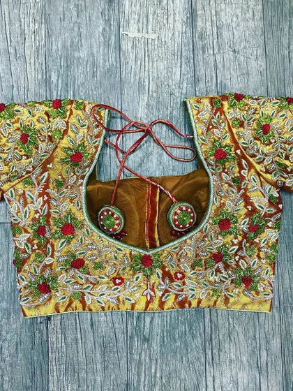 A fully embroidered blouse with a mix of silver and red threadwork on a gold base. The design includes floral and leaf patterns with bead highlights for a festive look.