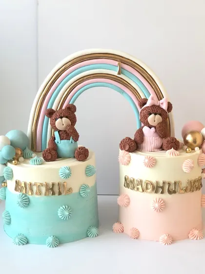 Double the love with this adorable set of teddy bear cakes for twins, connected by a beautiful rainbow.