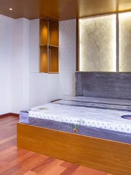 This master bedroom leans into quiet luxury with a stunning backlit stone panel as the focal point. The warm wooden flooring and ceiling add a grounded, timeless finish to the space.