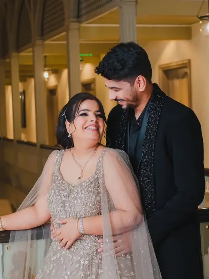 A candid moment of laughter and love between a couple during their wedding festivities, captured in an elegant indoor setting.