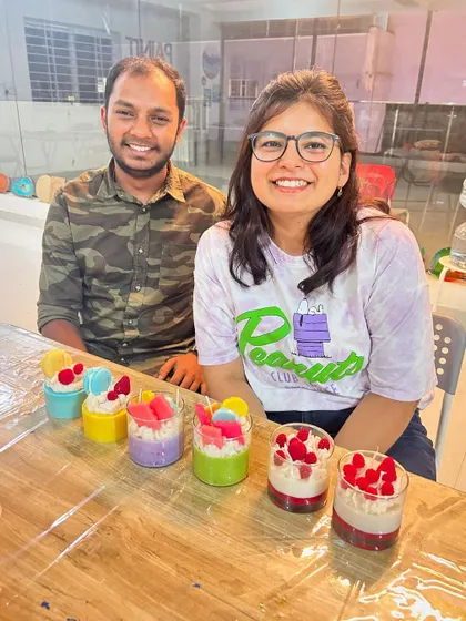 A happy couple posing with the colorful dessert candles they made together during a weekend workshop.