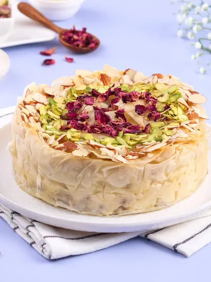 This is my fusion creation, the Baklava Cheesecake. It combines the creamy texture of cheesecake with the crispy, nutty, honey-soaked layers of traditional baklava, garnished with pistachios and rose petals.