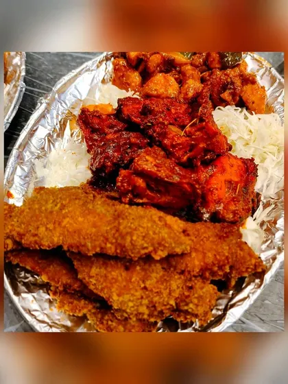 A simple yet satisfying plate of starters. This shows our crispy fried fish fillets and a portion of spicy chicken, served on a bed of shredded cabbage in a disposable foil plate, perfect for casual events.