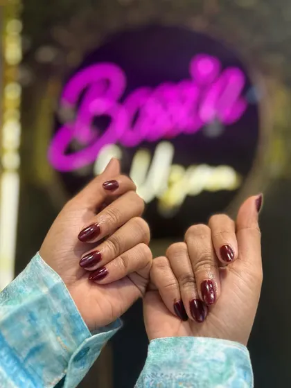 Both hands are showcased here, displaying the rich and consistent color of this classic red manicure against the salon's signature background.
