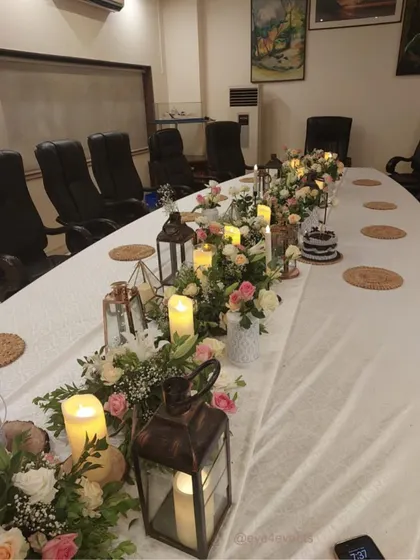 We can transform any space, even a corporate conference room, into a beautiful dining area. Here, we used a floral runner with rustic lanterns and candles to soften the room and create a warm, celebratory atmosphere.