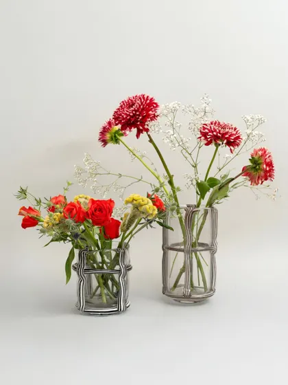 These delicate glass vases feature an external cage-like structure, adding a layer of visual complexity. They are perfect for holding small, airy bouquets that complement their intricate design.