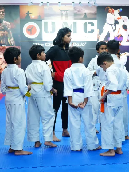 A coach gathers a group of young karate students for instruction. We foster a supportive environment where every child gets personal attention.