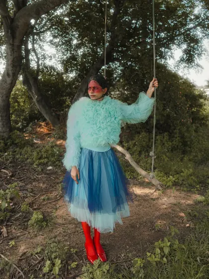 In this shot from 'SERPENTINE', the natural environment adds another layer to the story. The styling, with its vibrant colors and textures, stands out against the muted greens of the landscape, creating a striking visual narrative.