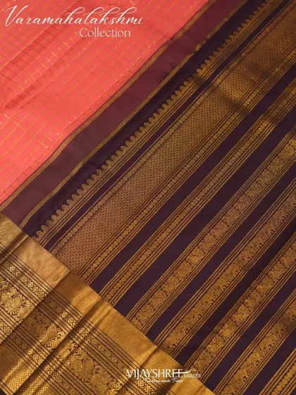 The deep purple pallu with its bands of gold zari creates a striking contrast with the pink body.