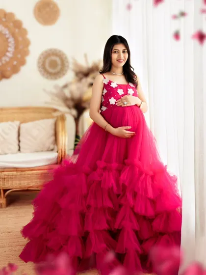 A beautiful portrait of a mom-to-be by the window, her pink gown glowing in the natural light.