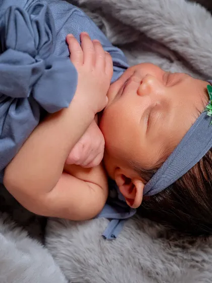 A close-up detail shot from the blue wrap session, focusing on the baby's face and tiny hands. These images are perfect for remembering just how small and delicate they were in their first days.