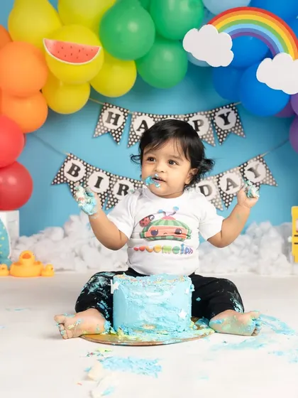 A colorful Cocomelon-themed cake smash is perfect for little fans of the show. This happy boy is having a wonderful time with his bright blue cake.