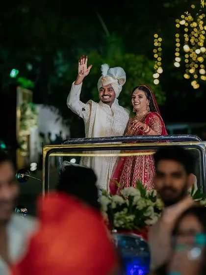 A grand exit in a vintage car, waving to cheering guests. This classic shot provides a perfect, storybook ending to the wedding celebration.