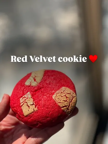 A vibrant red velvet cookie with white chocolate chunks, offering a classic flavor with a beautiful look.