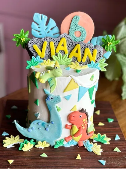 A dino-mite celebration! This dinosaur-themed setup features a tall cake with friendly fondant dinosaurs and a full set of matching cakesicles and treats for a roaring good time.