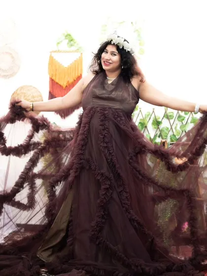 This client is having fun showing off the beautiful ruffles on our brown maternity gown during her indoor photoshoot.