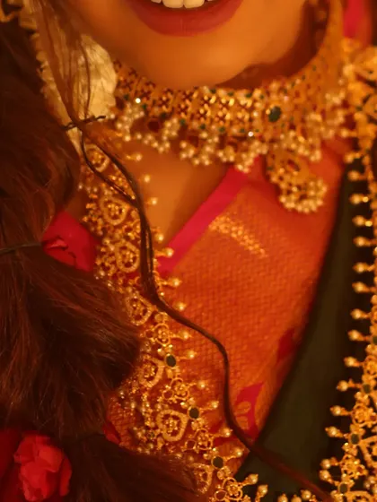 This detailed shot highlights the beautiful smile and the intricate choker necklace. The lip color was chosen to complement the jewellery and the pink in her saree, tying the whole look together.