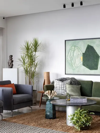 Blending old and new creates a unique and eclectic mix. This living room combines a modern green sofa with a rustic jute rug and a mix of contemporary and traditional art, telling a personal narrative.