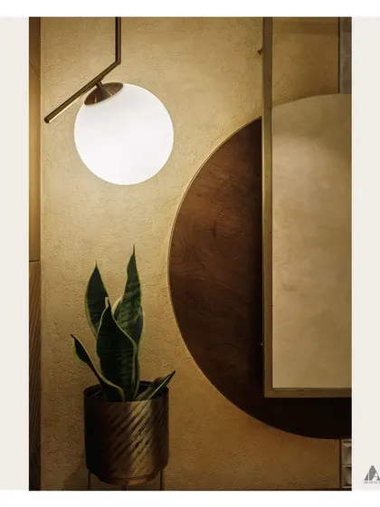 A detail shot focusing on the interplay of light, texture, and form. The modern globe pendant light contrasts beautifully with the warm wood panels and the organic shape of the snake plant.