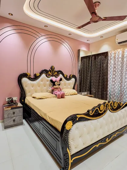 A beautiful girl's bedroom with a pink accent wall featuring elegant arch-shaped grooves. The classic black and white carved bed adds a touch of royal charm to the room.
