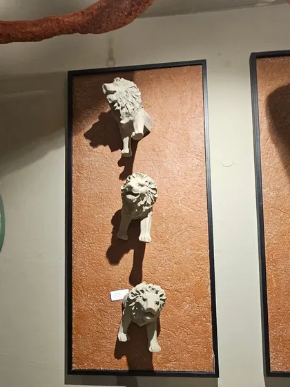 This unique wall art features a series of lion heads emerging from the surface, creating a bold and dramatic statement piece for an exterior or interior wall.