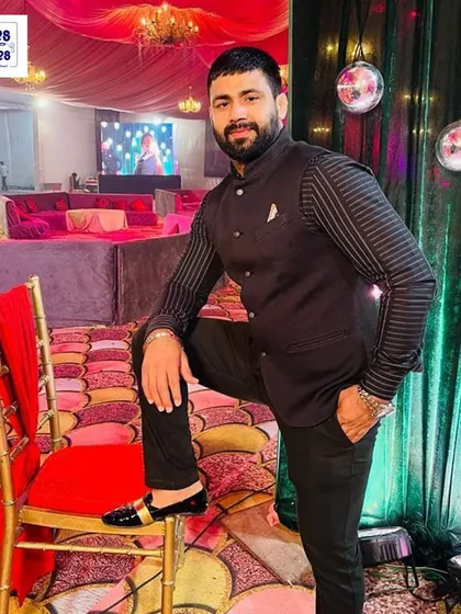 A client dressed for a wedding party in a custom black Jodhpuri suit with subtle striped details. The fit is tailored to be modern and comfortable.