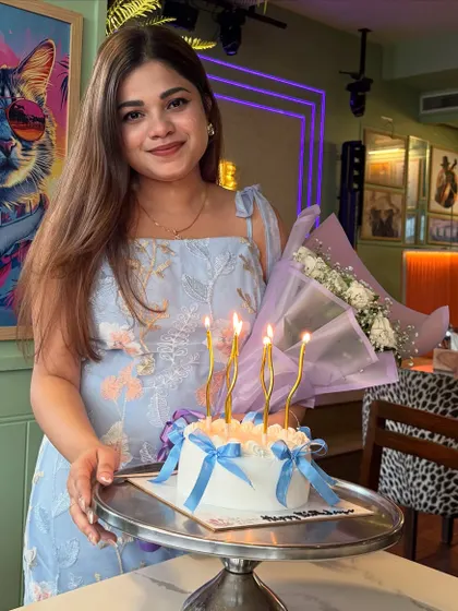 A happy client celebrating her birthday with a simple and chic blue and white cake, decorated with delicate blue ribbons.