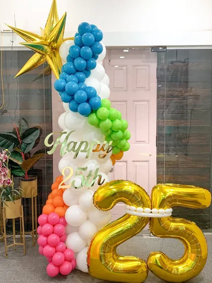 A vibrant and colorful column celebrating a 25th birthday. The rainbow spiral of balloons climbing the pillar, topped with a golden star, makes for a joyful and eye-catching party decoration.