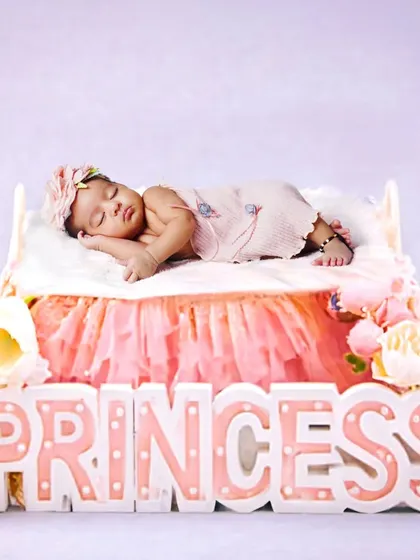 A sweet newborn princess theme, with the baby sleeping peacefully on a tiny bed. The 'Princess' marquee light adds a lovely touch to this delicate setup.